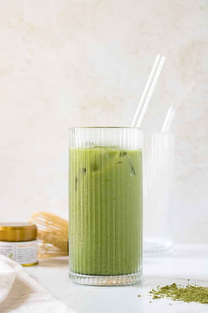 Side view of iced matcha in a glass with straw.
