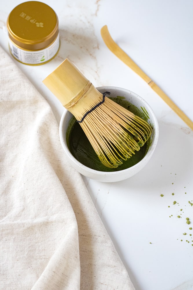 Matcha paste with a bamboo whisk.