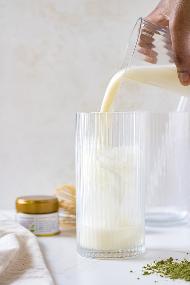 Woman's hand pouring milk into a glass.