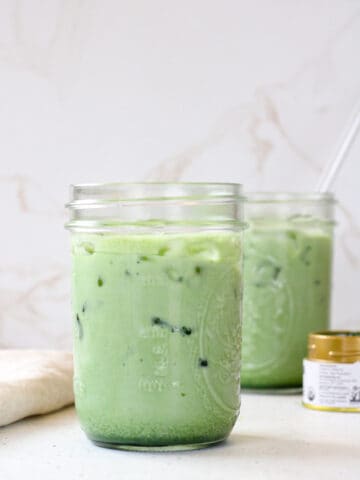 Side view of iced matcha lattes in mason jars.