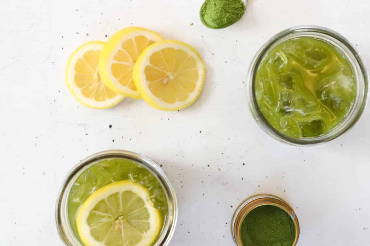 Overhead view of lemonade with lemon slices and matcha powder.