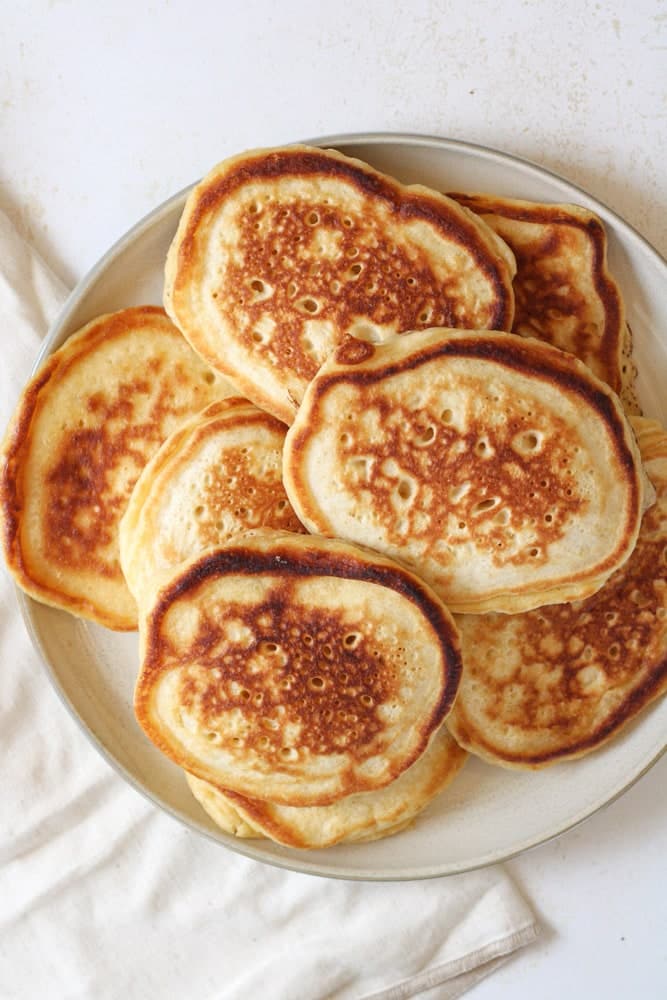 Overhead image of stacked old fashioned pancakes on a plate.