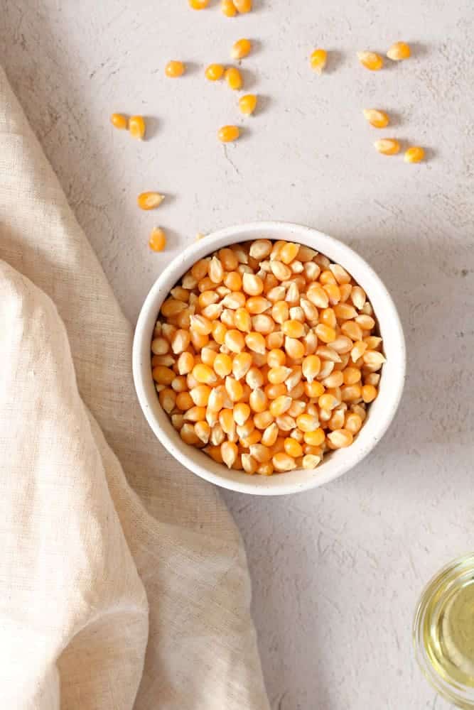 Overhead view of popcorn kernels and vegetable oil on a table. 