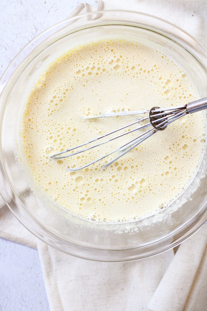 Egg yolks tempered with hot milk in a large bowl. 