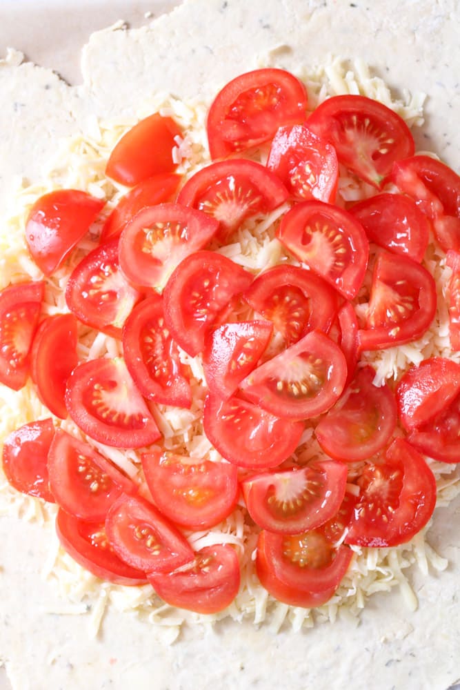 Overhead image of tomatoes and cheese on a pastry dough.