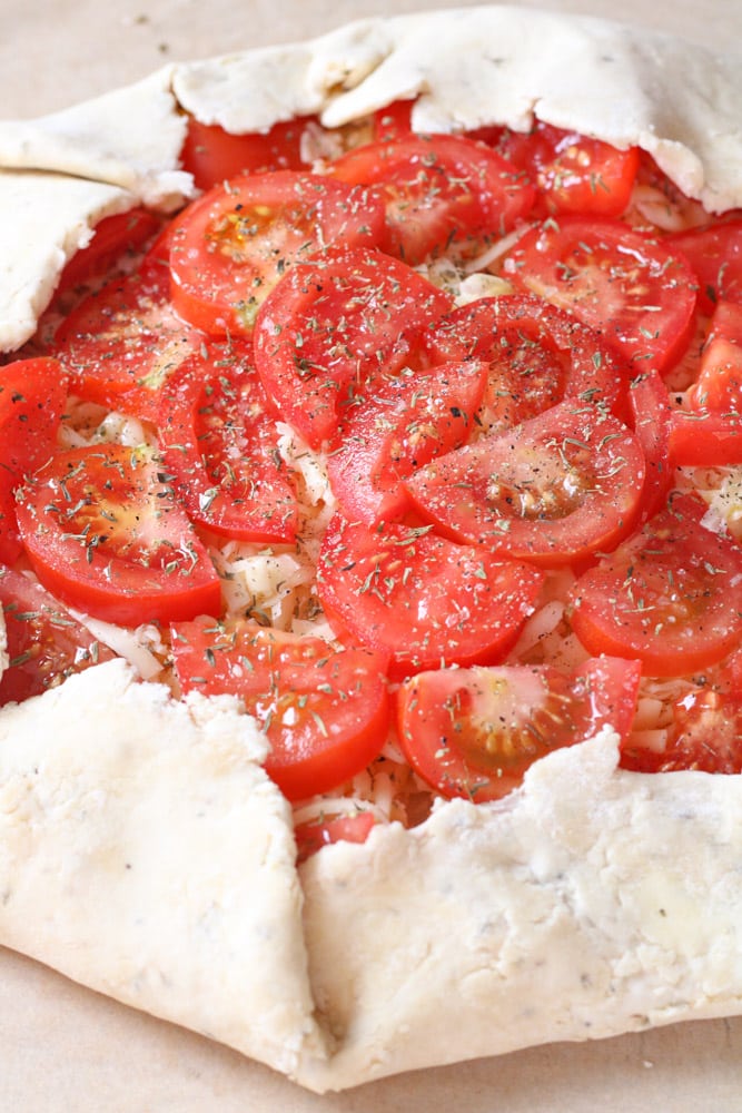 Side view of an unbaked tomato galette.