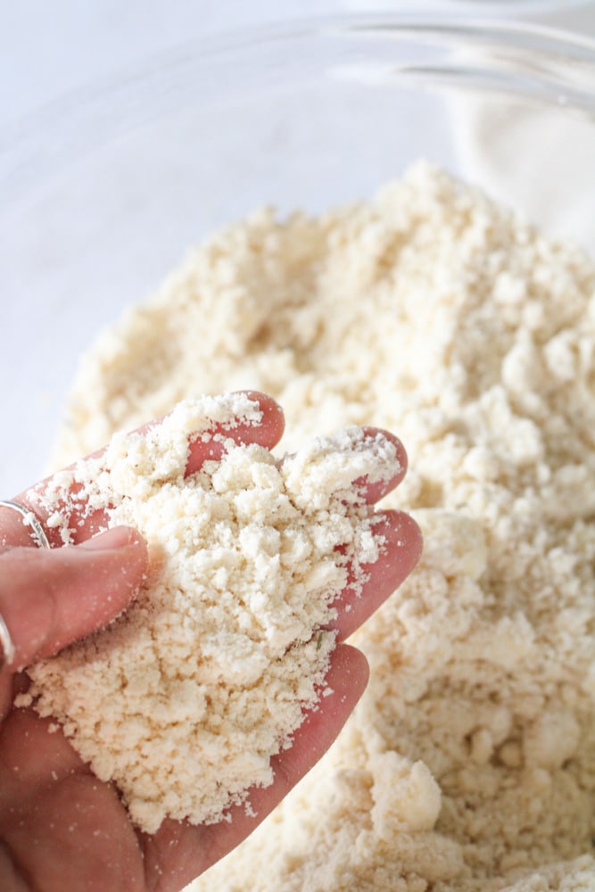 Woman's hand holding up butter and flour crumbles.