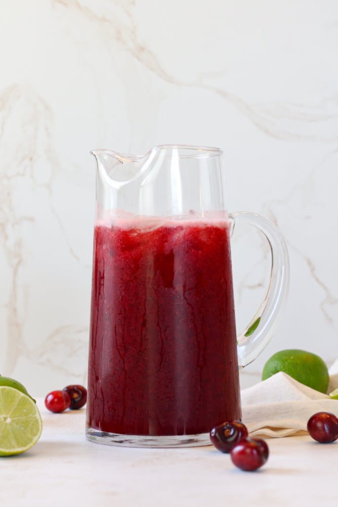 Side view of cherry limeade in a pitcher.