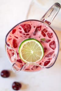 Overhead image of cherry limeade in pitcher with lime slice.