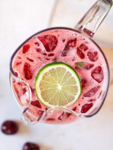 Overhead image of cherry limeade in pitcher with lime slice.