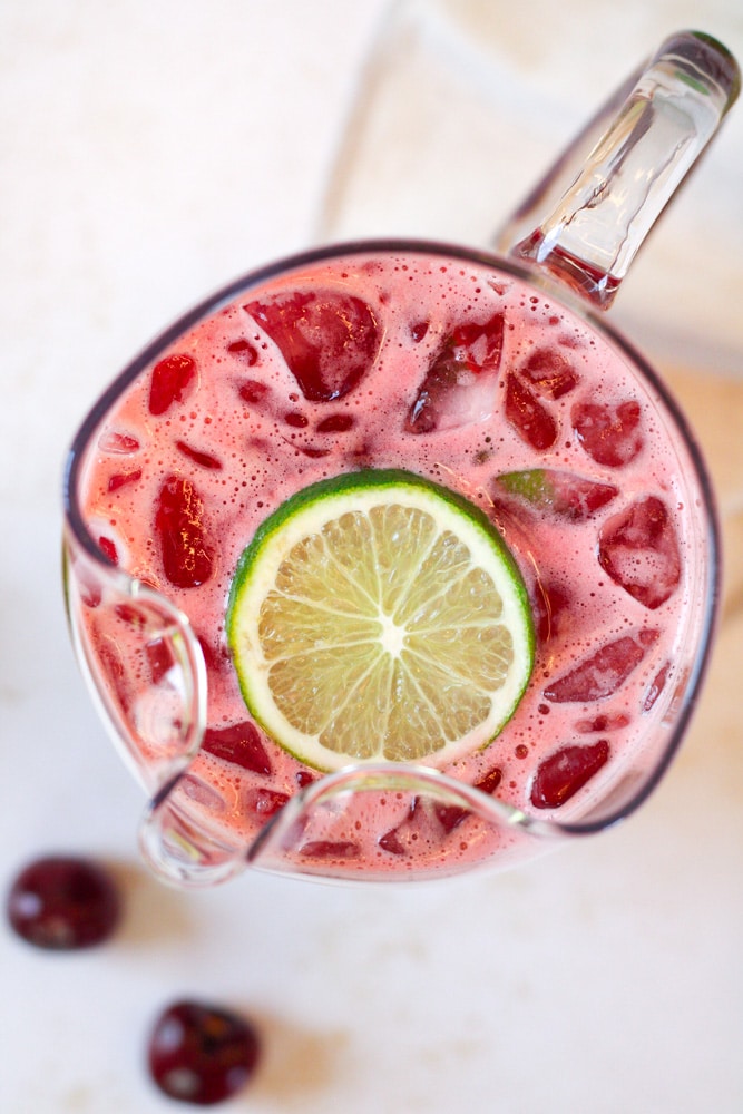 Overhead image of cherry limeade in pitcher with lime slice.