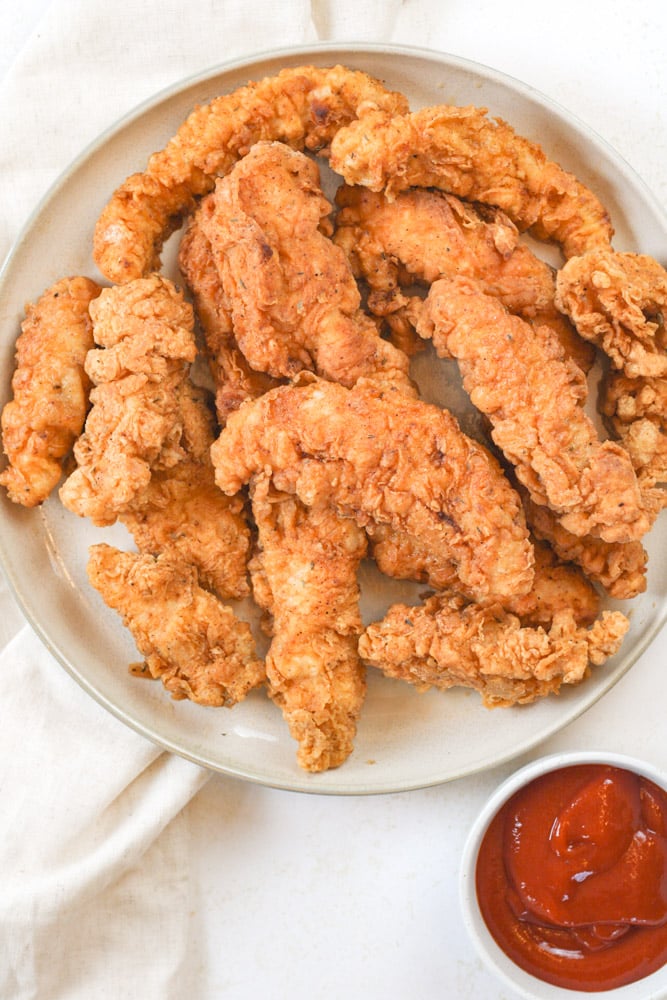 Plate of crispy chicken tenders with a bowl of ketchup.