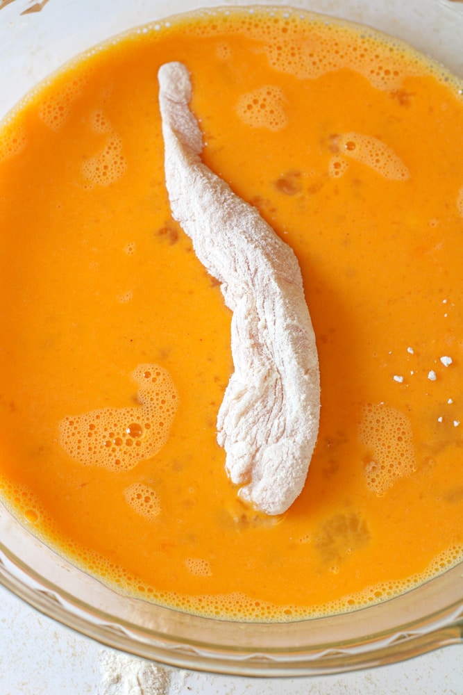 Floured chicken tender in a egg wash.