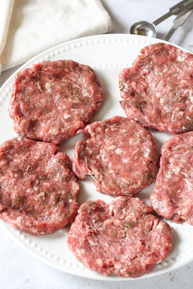 ¾ view of raw sausage patties on a plate.