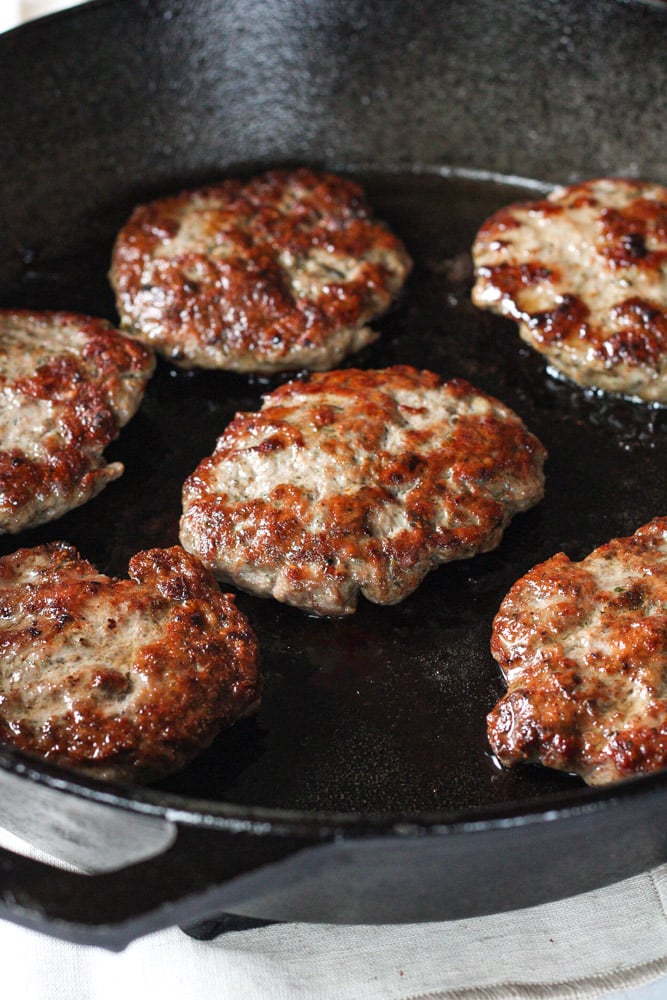 Side view of sausage patties in a cast iron skillet.