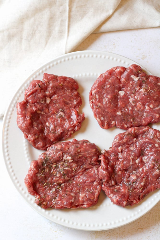 Raw lamb patties on a plate.