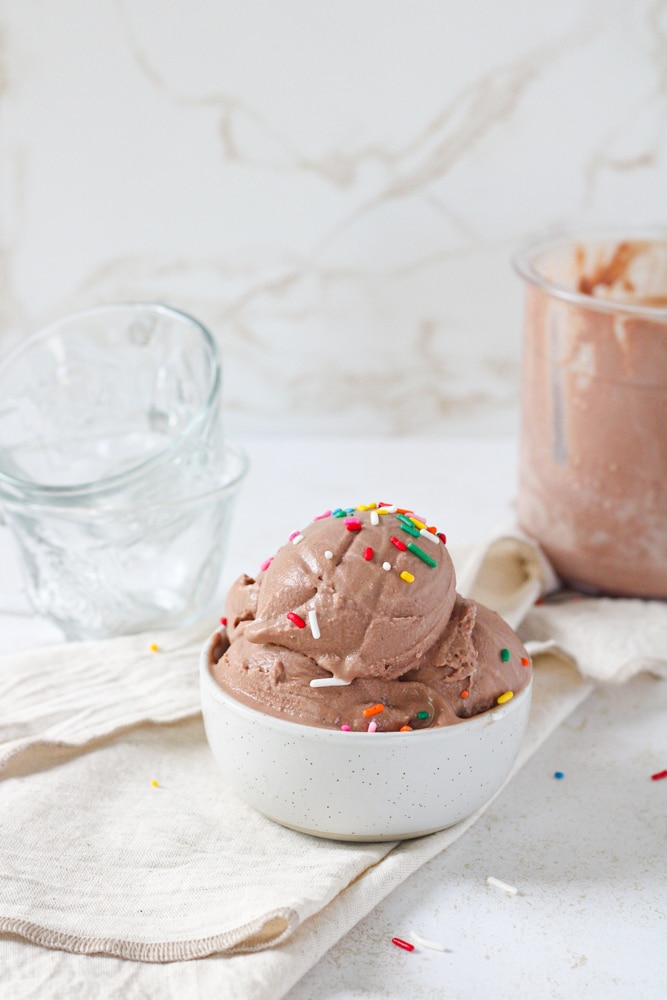 ¾ view of chocolate ice cream in a bowl topped with rainbow sprinkles.