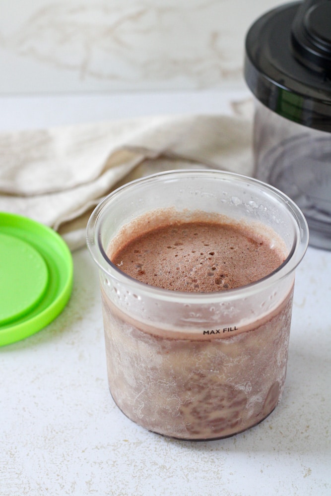 Side view of a frozen chocolate ice cream in a pint container.