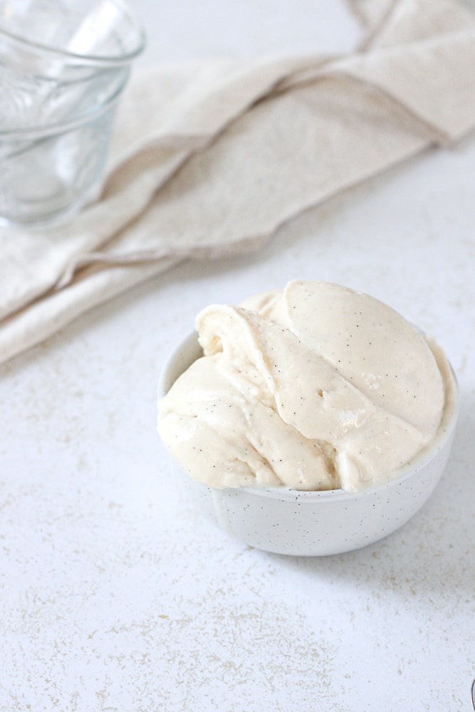 Close up image of a scoop of vanilla ice cream in a bowl.