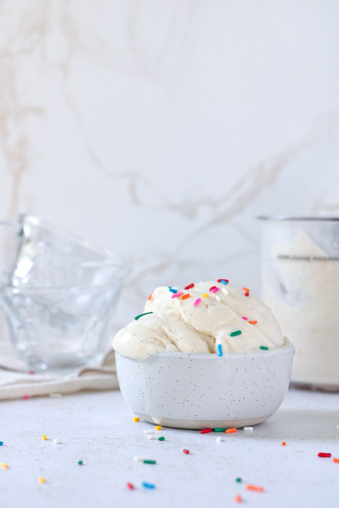 Side view of a scoop of ice cream in a bowl with sprinkles.
