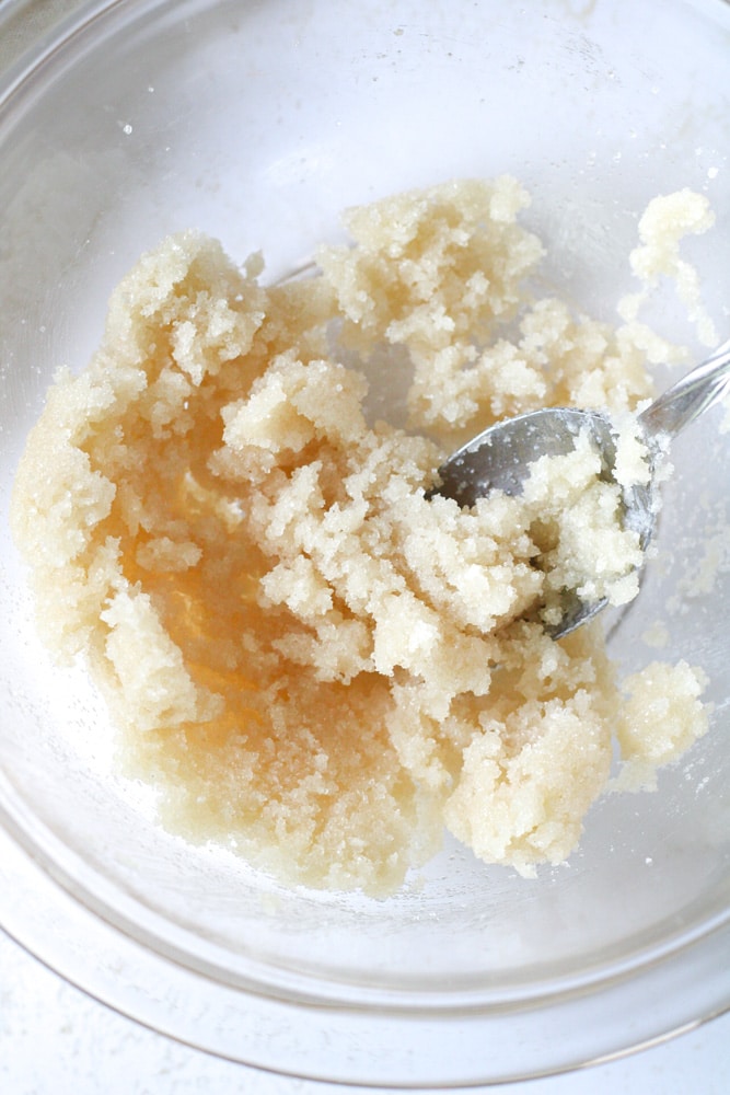 Sugar mixed with cream cheese in a bowl with a spoon.