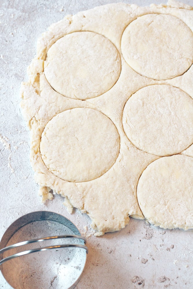 Close up of biscuit dough with a biscuit cutter.