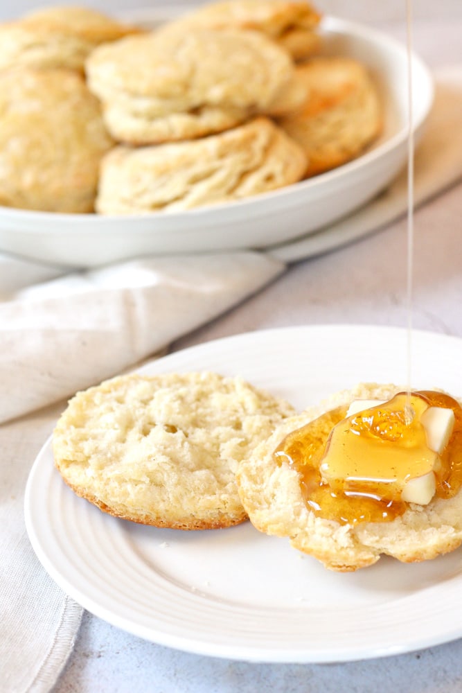 Sliced biscuit with butter and a drizzle of honey.