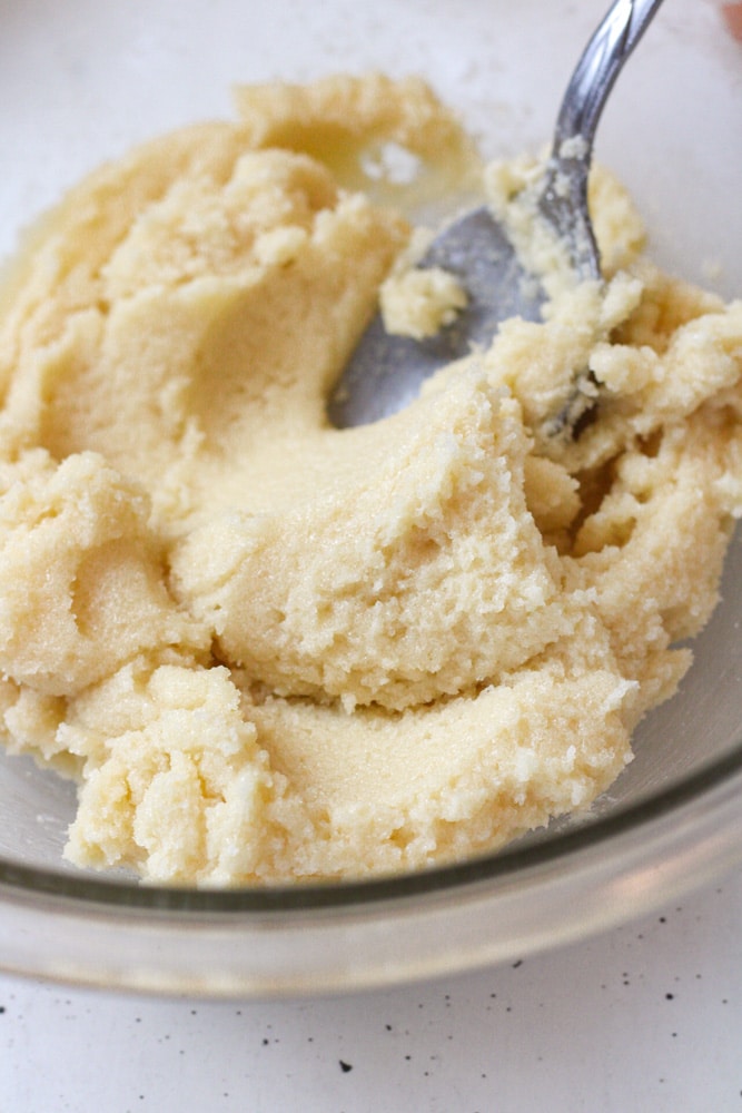 Close up image of butter and sugar creamed together in a bowl with a spoon.