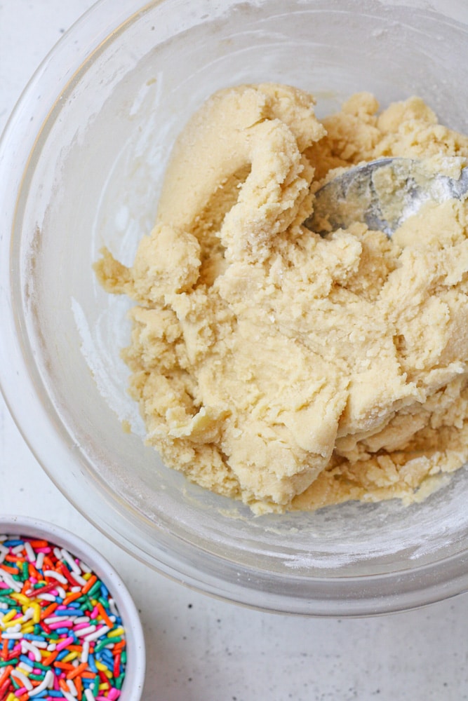 Sugar cookie dough in a bowl with a spoon.