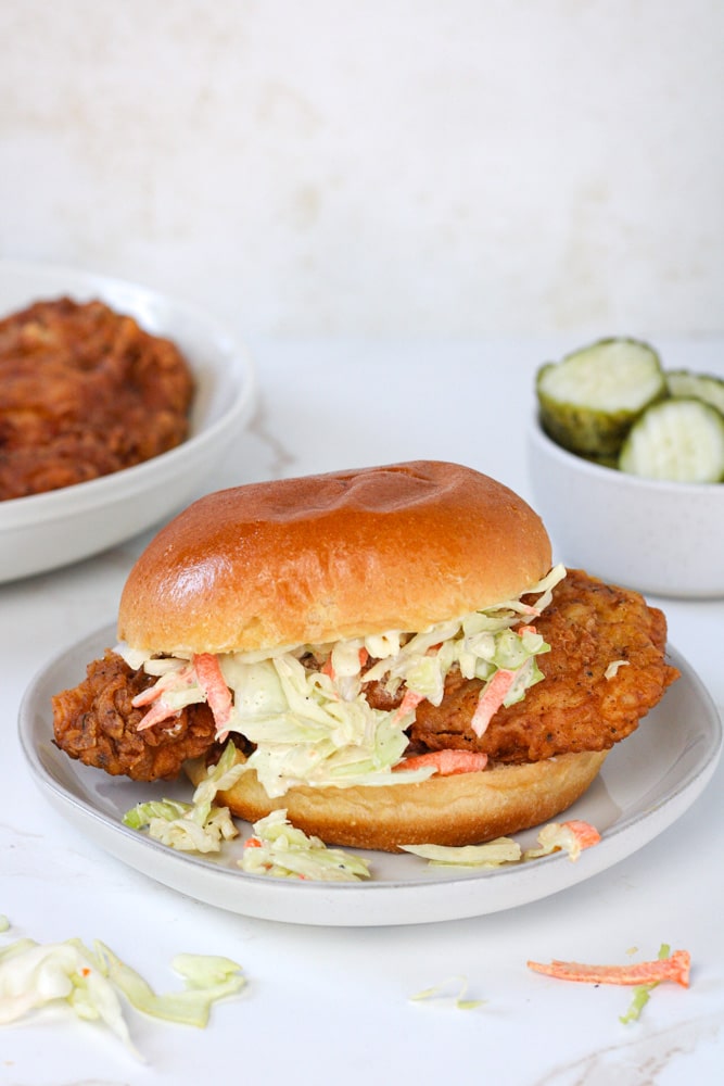 Side view of fried chicken sandwich on a plate with coleslaw.