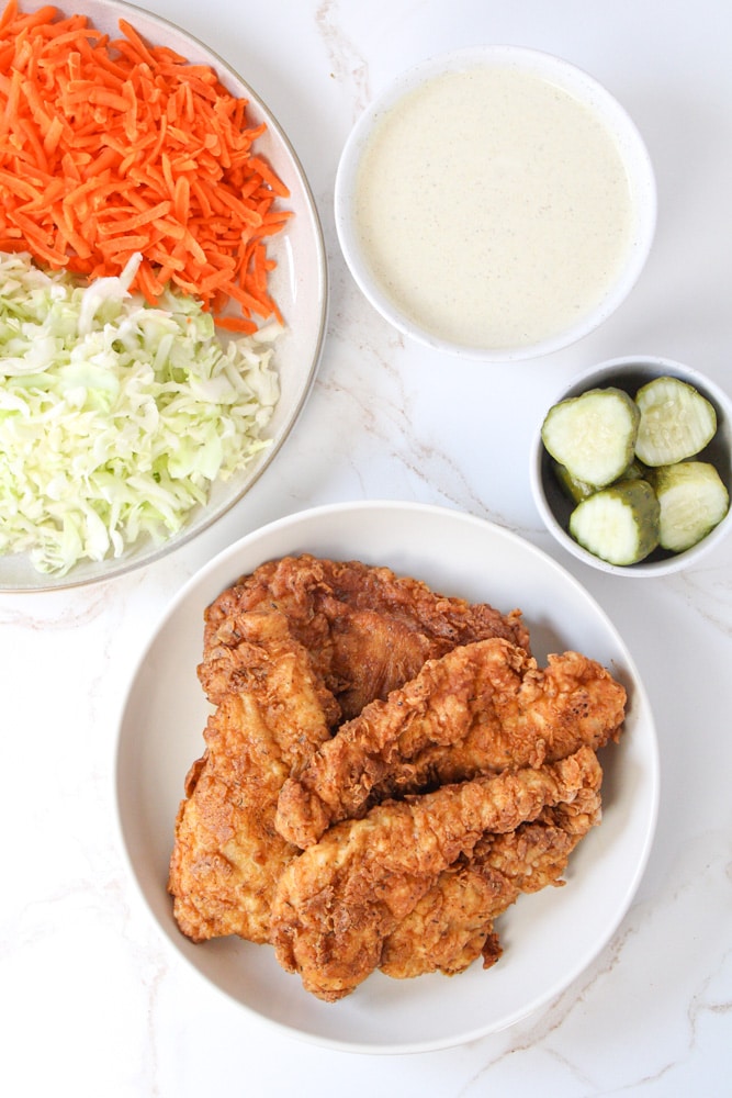 Overhead image of chicken fried chicken on a plate with coleslaw and pickles near by.