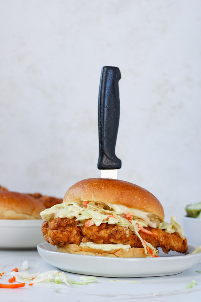 Side view of chicken sandwich with a knife sticking out of the top.