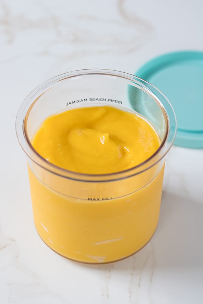 Blended mango sorbet base inside the ninja creami pint container.