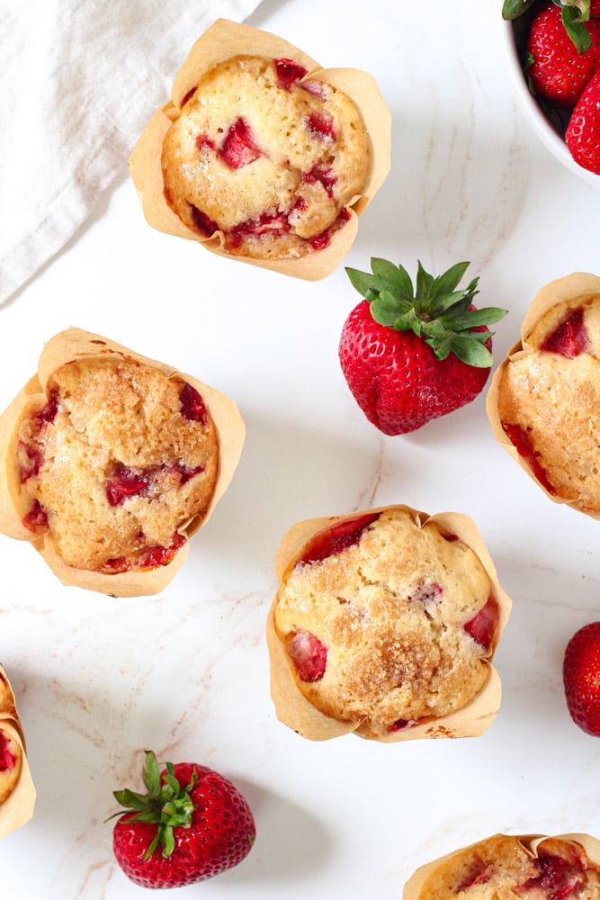 Overhead image of muffins with fresh strawberries on a table.