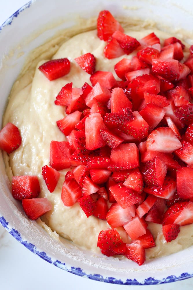 Chopped strawberries on top of muffin batter in a large mixing bowl.