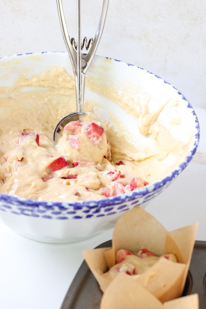 Ice cream scoop in mixing bowl with muffin batter.