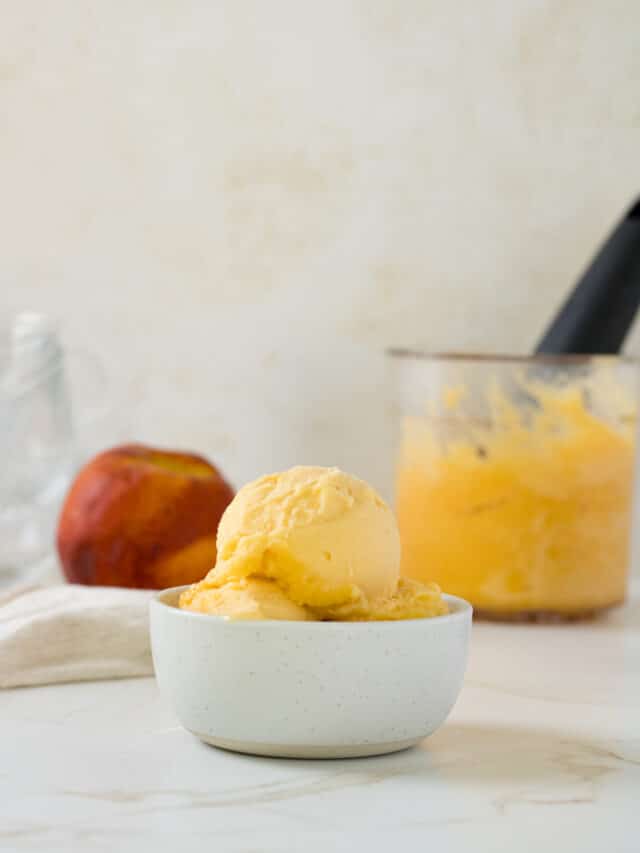 Side view of scoops of peach sorbet in a bowl.