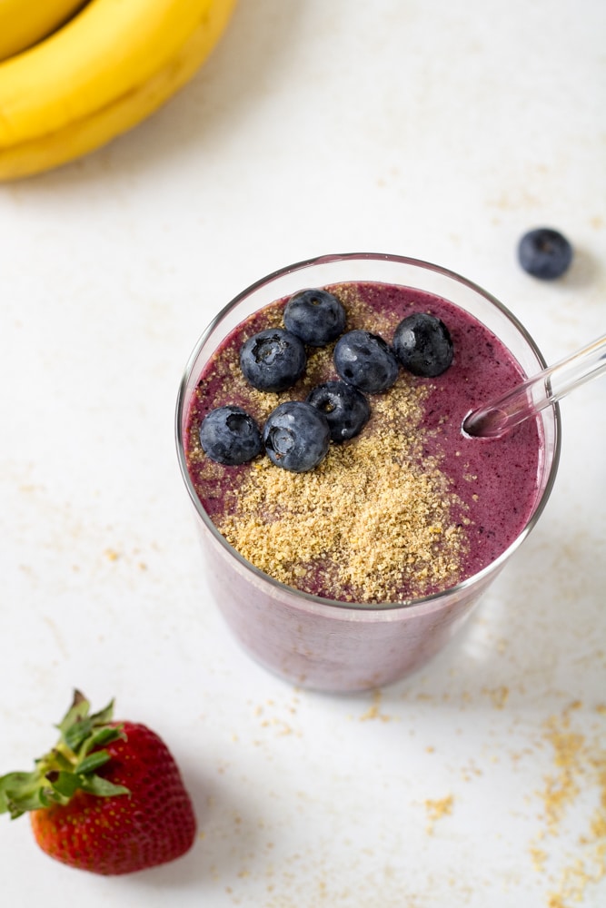 Smoothie in a glass with flaxseeds and blueberries.