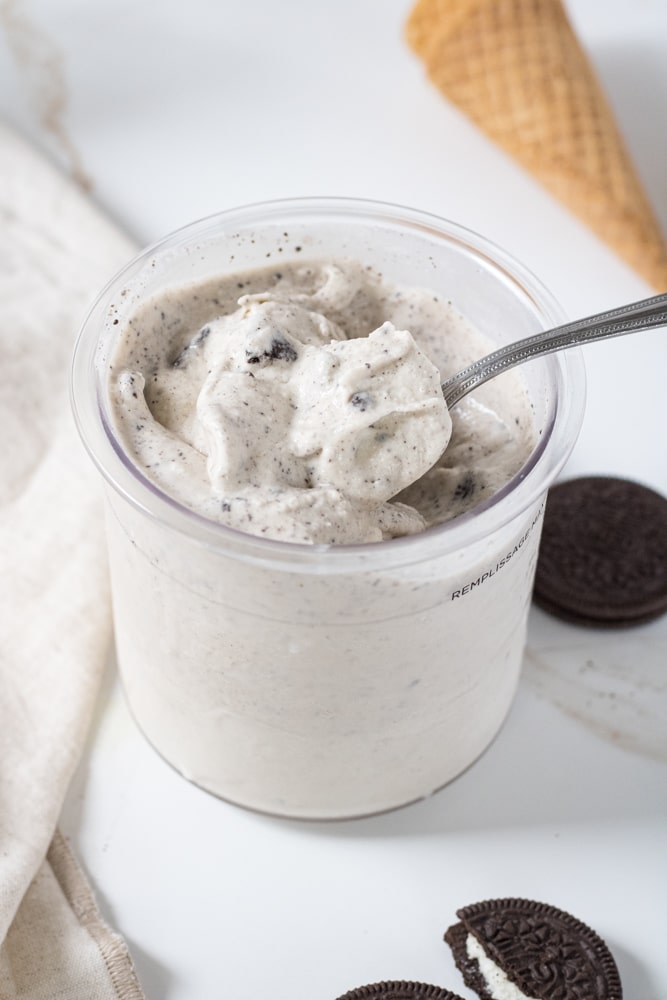Cookies and cream ice cream in a pint container with a spoon.
