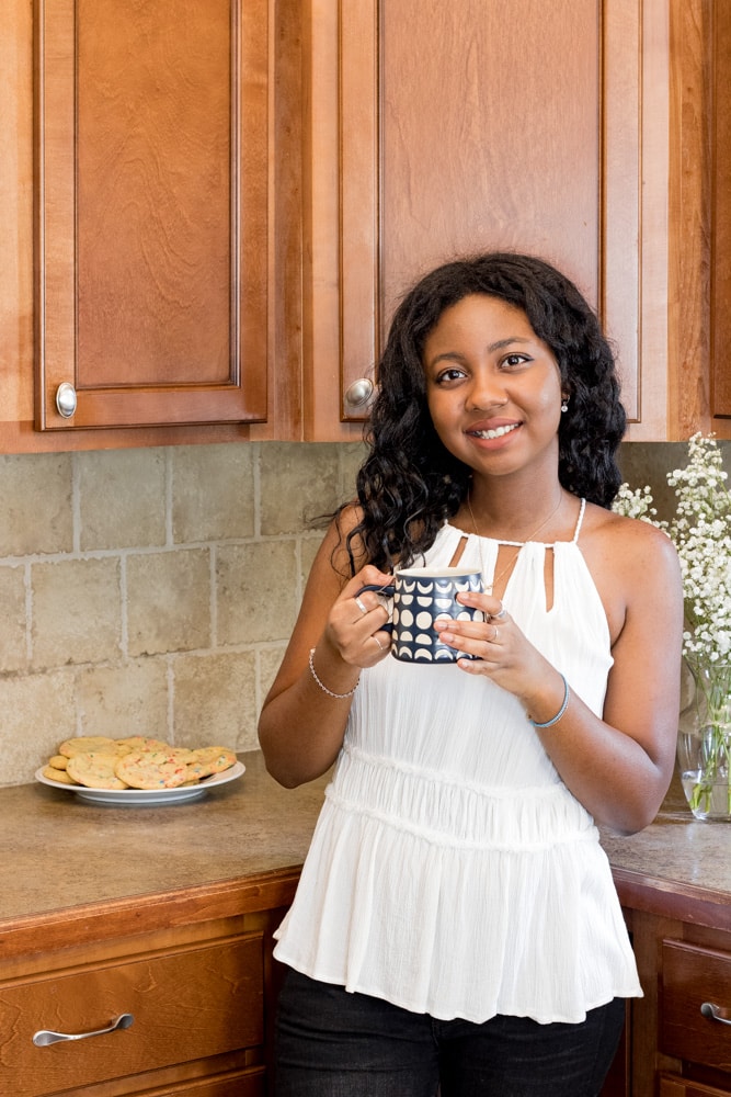 Woman smiling and holding a cup of tea in the kitchen.