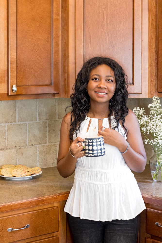 Woman smiling and holding a cup of tea.