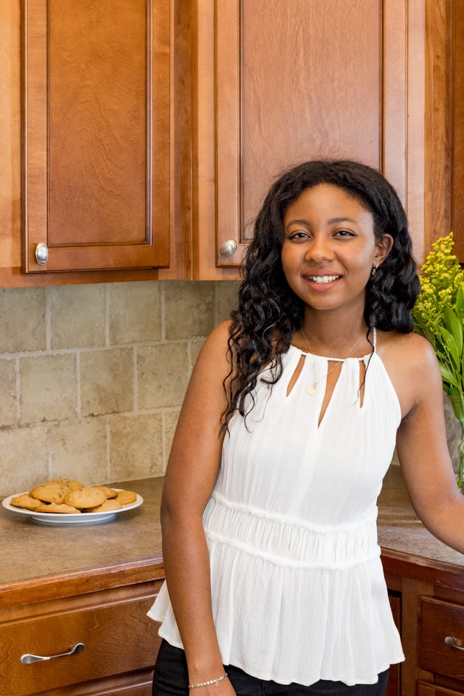 Woman smiling in the kitchen next to a plate of cookies.