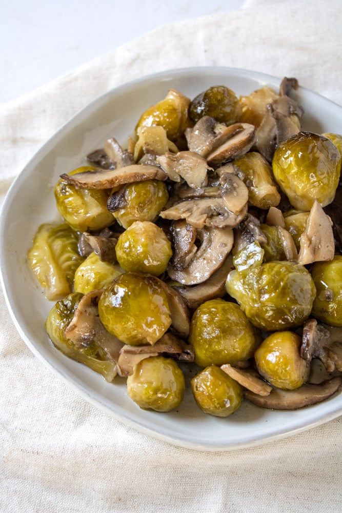 ¾ image of roasted brussels sprouts with mushrooms on a plate.