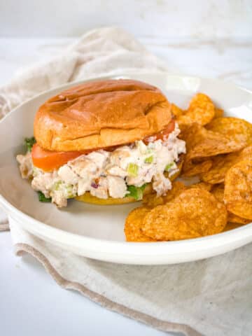 Smoked chicken salad sandwich on a plate with chips.