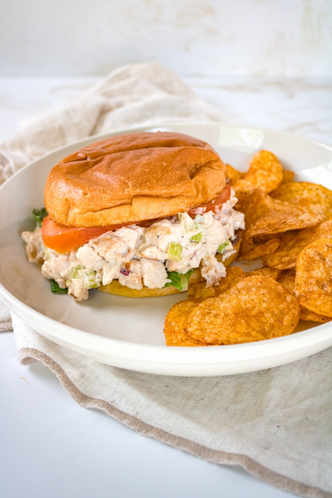 Smoked chicken salad sandwich on a plate with chips.