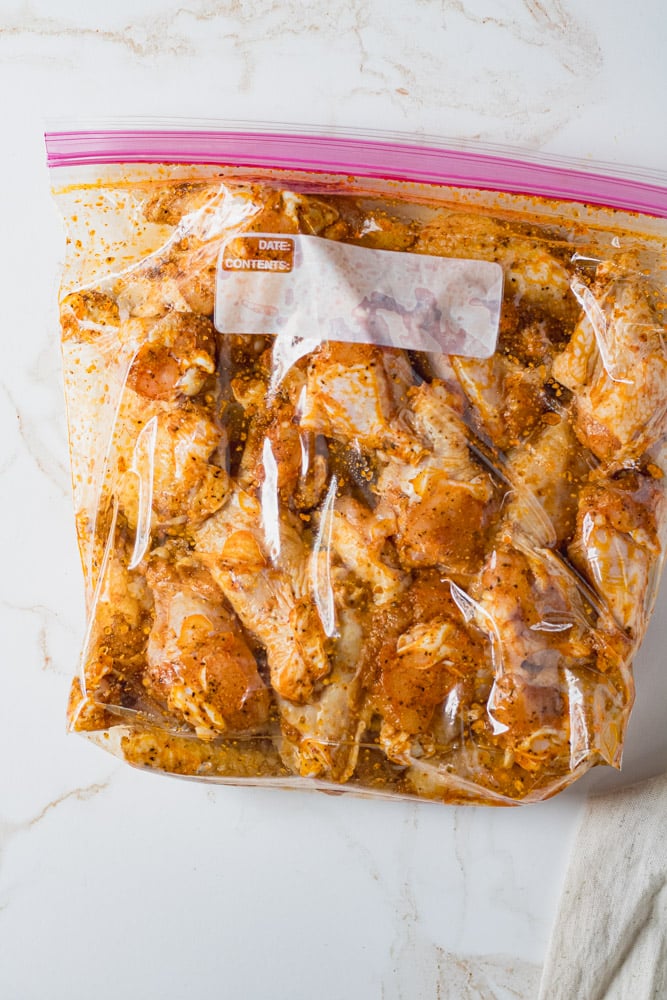 Raw wings in a gallon bag coated in seasonings and oil. 