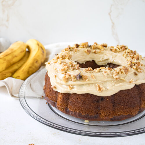 Banana nut cake on a plate with frosting.