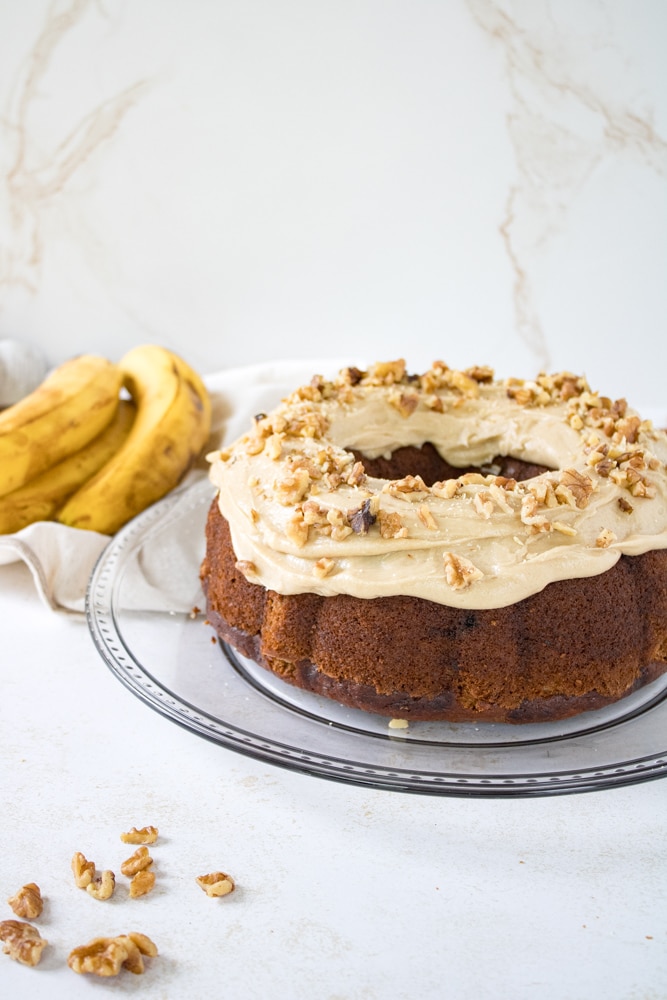 Banana nut cake on a plate with frosting.