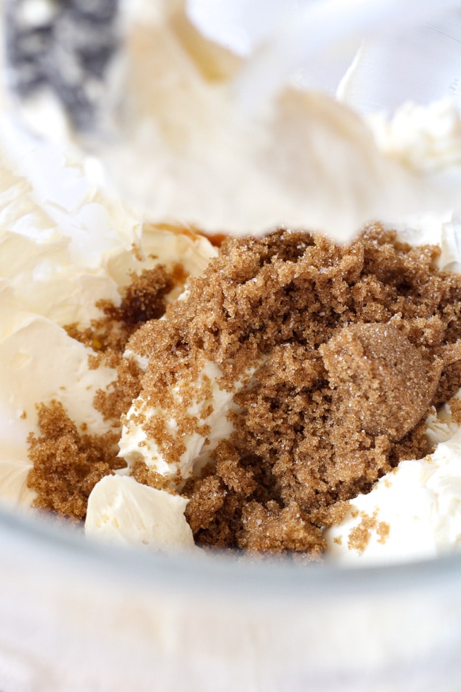 Brown sugar on top of whipped cream cheese in a stand mixer bowl.