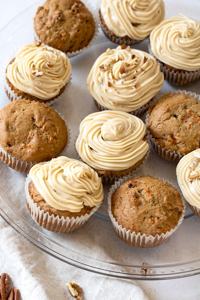 Carrot cake cupcakes on a plate with frosting.